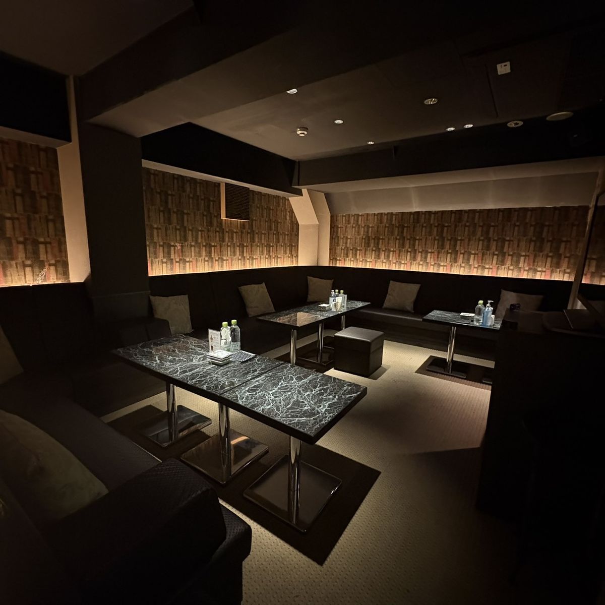 ZEUS & HERA 店内：間接照明に照らされた黒いソファのフロア